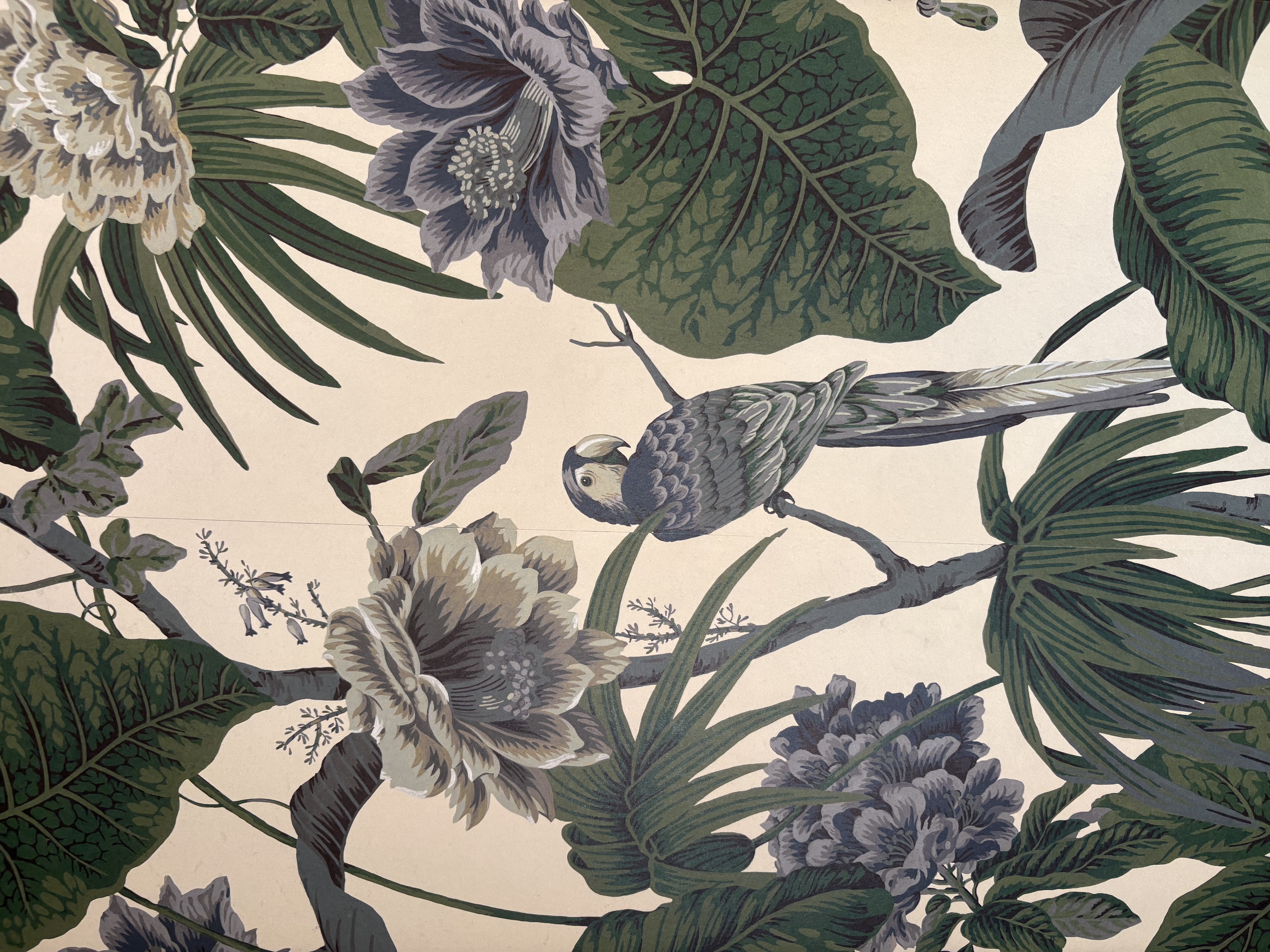 Détail d'une tapisserie sur laquelle est représenté un perroquet posé sur une branche fleurie d'un arbre exotique.