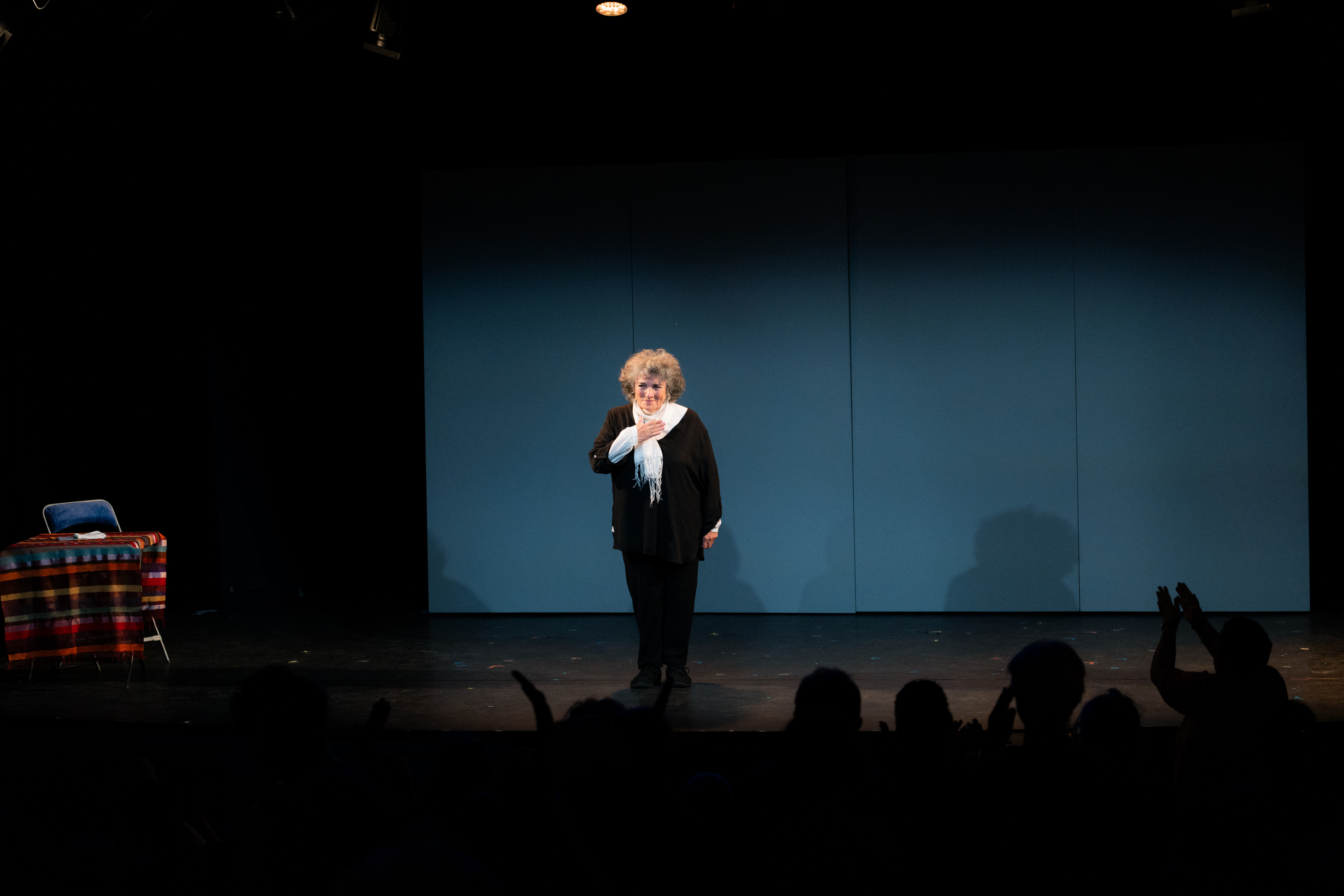 Sur scène une femme debout salue le public une main posée sur son coeur.