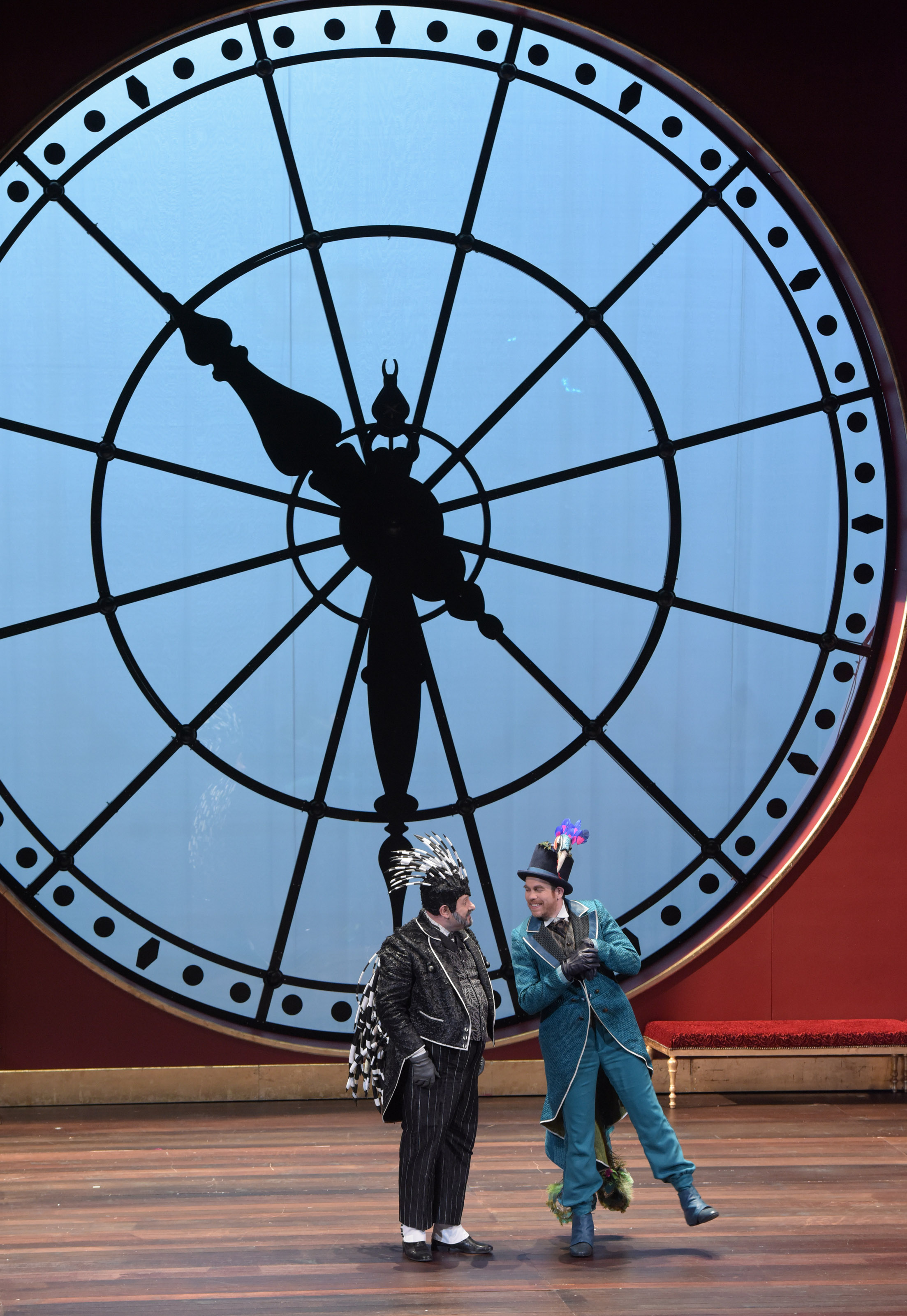 Descriptif de la photo: Devant une horloge murale géante, deux personnages avec chapeau semblent dialoguer.