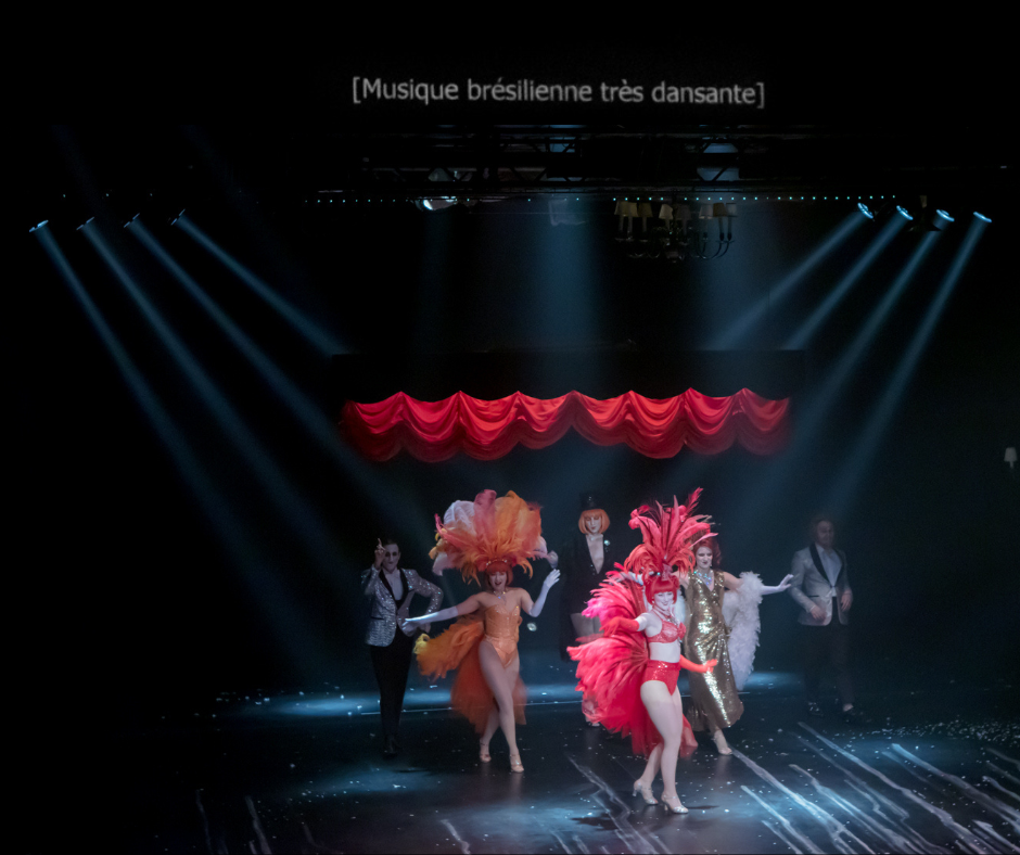 6 personnes costumées dansent sur une scène dans un décor de cabaret. Au-dessus de la scène est projeté un texte en surtitre. On y lit: "Musique brésilienne très dansante".