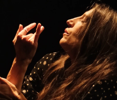 Visage d'une femme de profil. Elle porte des cheveux longs, ses yeux sont fermés dans une intense concentration. Elle lève une main à hauteur de son visage comme une danseuse de flamenco.