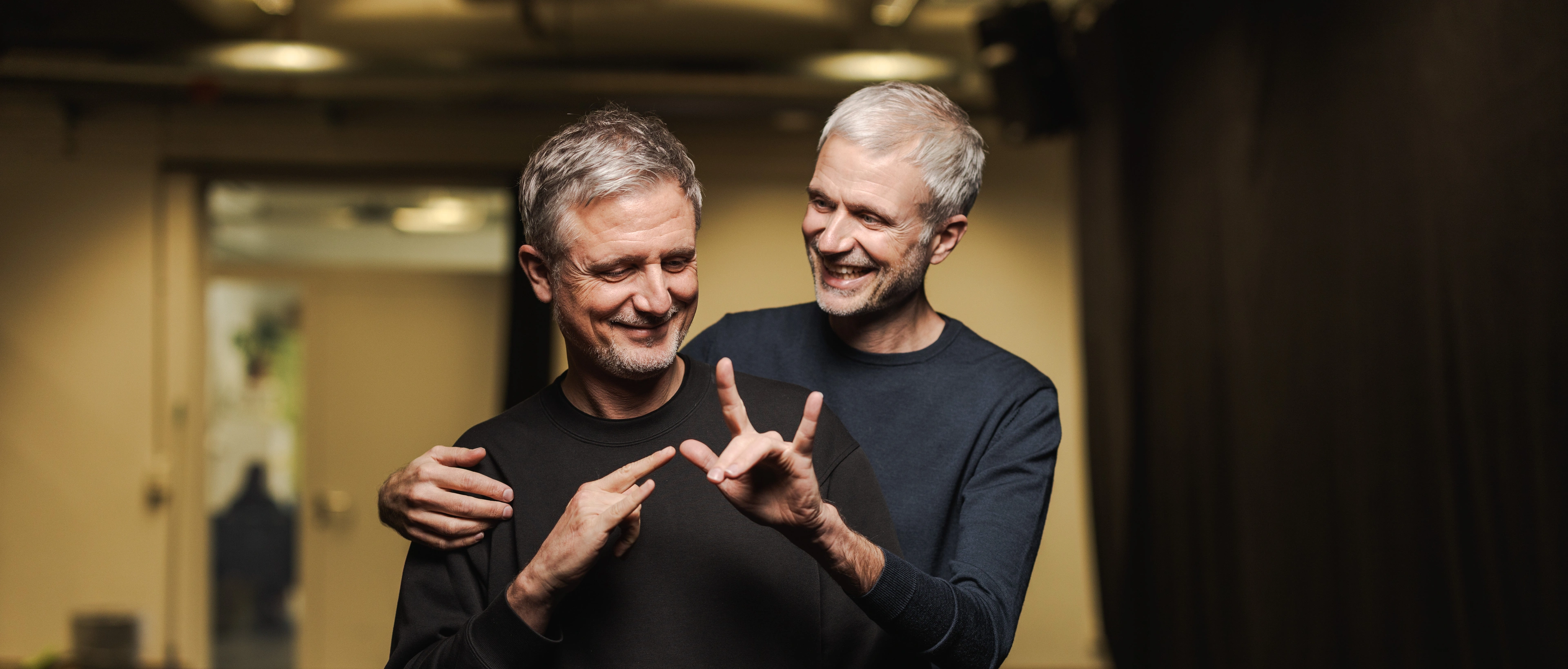 Christian et François Gremaud sont côte à côte et font tous deux le signe "Je t'aime" en LSF.